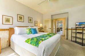 Una habitación de hotel con una cama, televisión, escritorio y puerta que da a otra habitación.