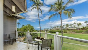 Ein Balkon mit Tisch und Stühlen mit Blick auf einen Golfplatz und Palmen.