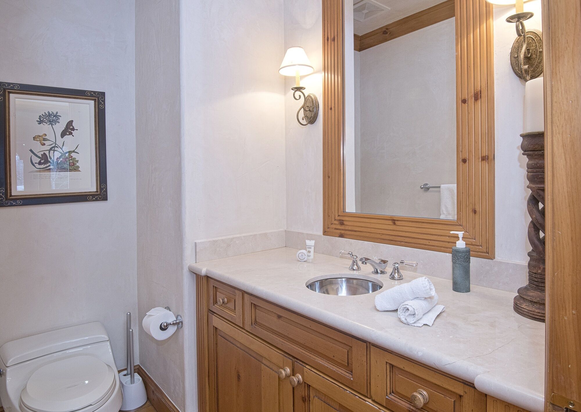 Une salle de bain équipée d’un lavabo, d’un miroir, de toilettes et d’une œuvre d’art encadrée.