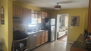 Una cocina con armarios de madera, un refrigerador de acero inoxidable y una zona de comedor con una mesa y sillas.