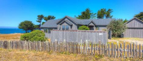 A coastal property with multiple cabins, a wooden fence, and a clear view of the ocean.