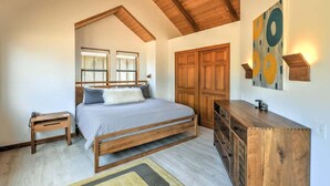 Une chambre à coucher avec un lit, une tête de lit en bois, des tables de chevet, une commode et un tableau au mur.