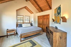Un dormitorio con una cama, cabecera de madera, mesitas de noche, cómoda y un cuadro en la pared.