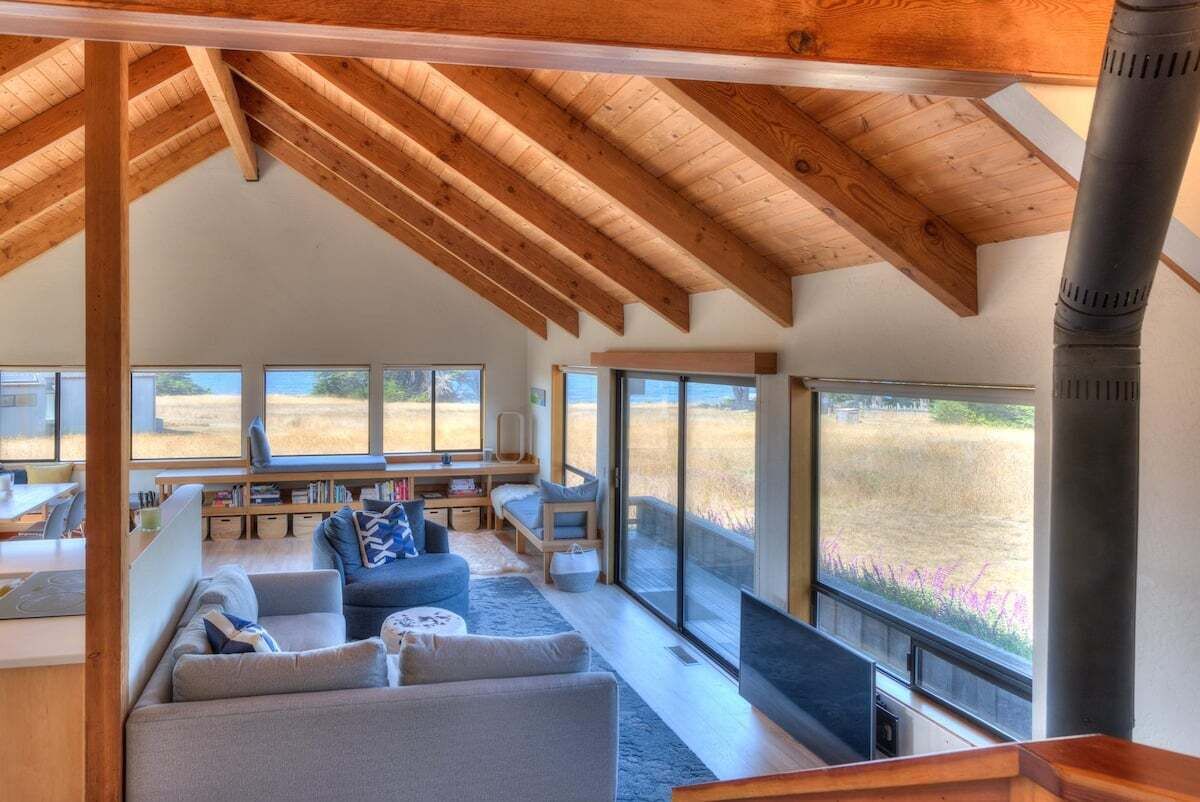 Amplia sala de estar con techo alto, ventanas grandes y chimenea.