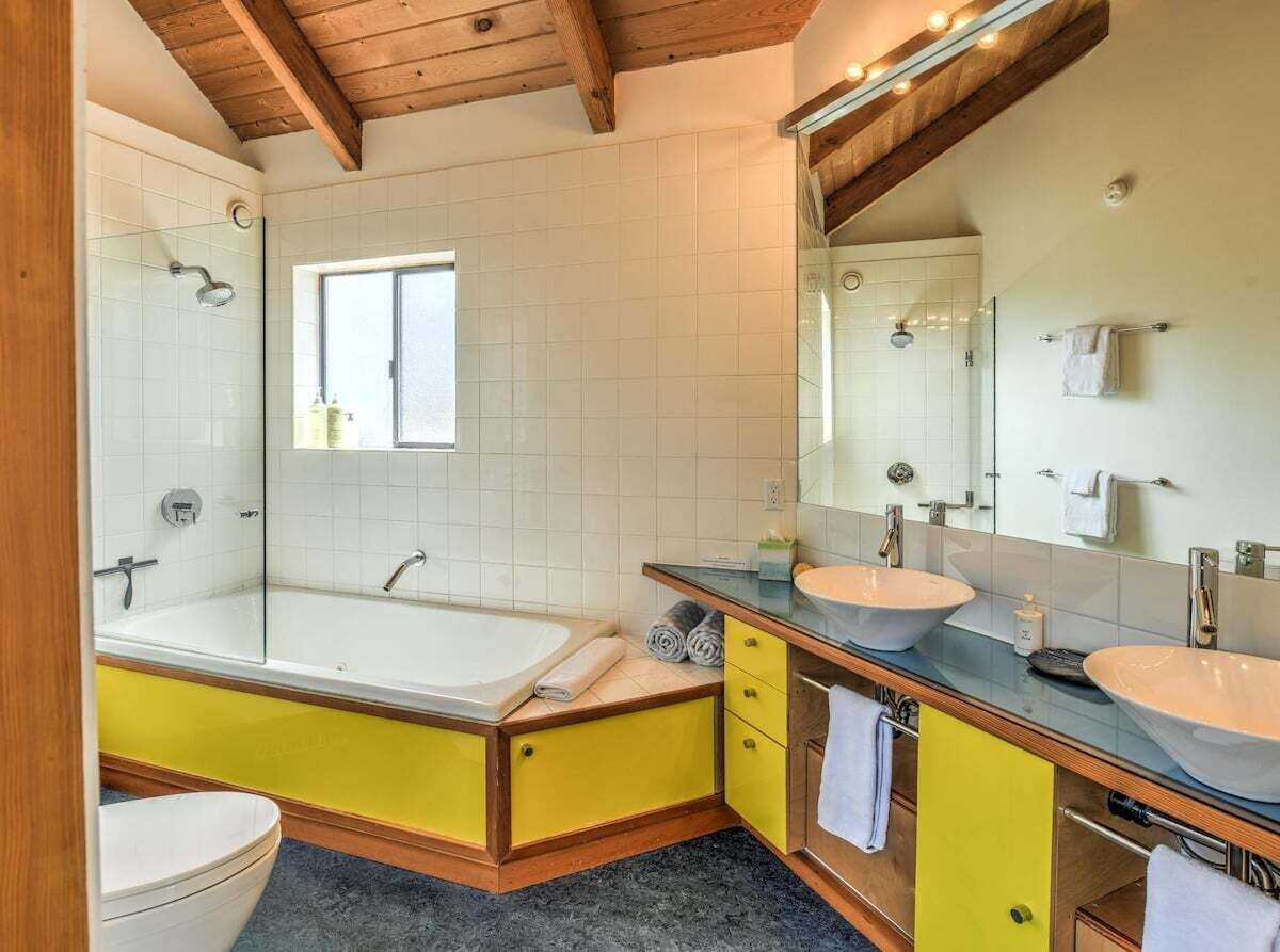 Ein Badezimmer mit einer Badewanne, zwei Waschbecken, einer Toilette und einem großen Spiegel.