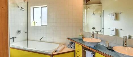 Ein Badezimmer mit einer Badewanne, zwei Waschbecken, einer Toilette und einem großen Spiegel.