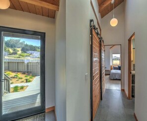 A hallway with a sliding door leading to a deck with a view of a landscaped garden.