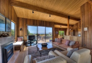 A spacious living room with a fireplace, a television, and a large window offering a view of the outdoors.
