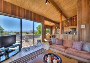 A spacious living area with a large television, a sofa, and a dining table.