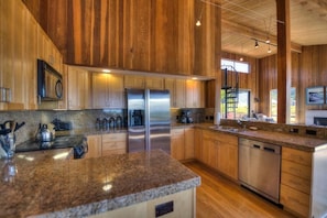 A kitchen with wooden paneling, stainless steel appliances, granite countertops, and a built-in dishwasher.