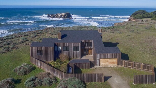 A coastal house with a large garage, a covered porch, and a view of the ocean. - Berk | Ocean Views, Fireside Nights & Hot Tub (Sea Ranch)