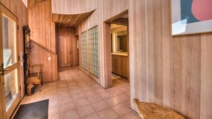 A wooden interior hallway with a staircase, a door, and a window. - Berk | Ocean Views, Fireside Nights & Hot Tub (Sea Ranch)