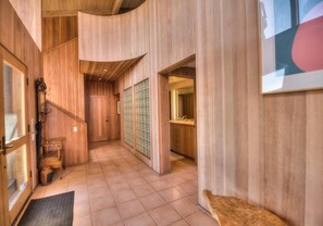 A wooden interior hallway with a staircase, a door, and a window. - Berk | Ocean Views, Fireside Nights & Hot Tub (Sea Ranch)