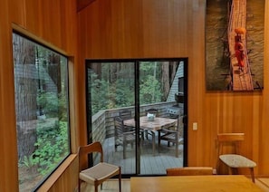 A wooden interior with a sliding glass door leading to an outdoor deck. - Forest House | Tranquil Escape & Trails (The Sea Ranch)