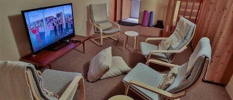 A living room with a television, reclining chairs, a small table, and a staircase.