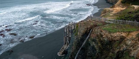 A coastal landscape with a wooden walkway leading to a cliff overlooking the ocean.