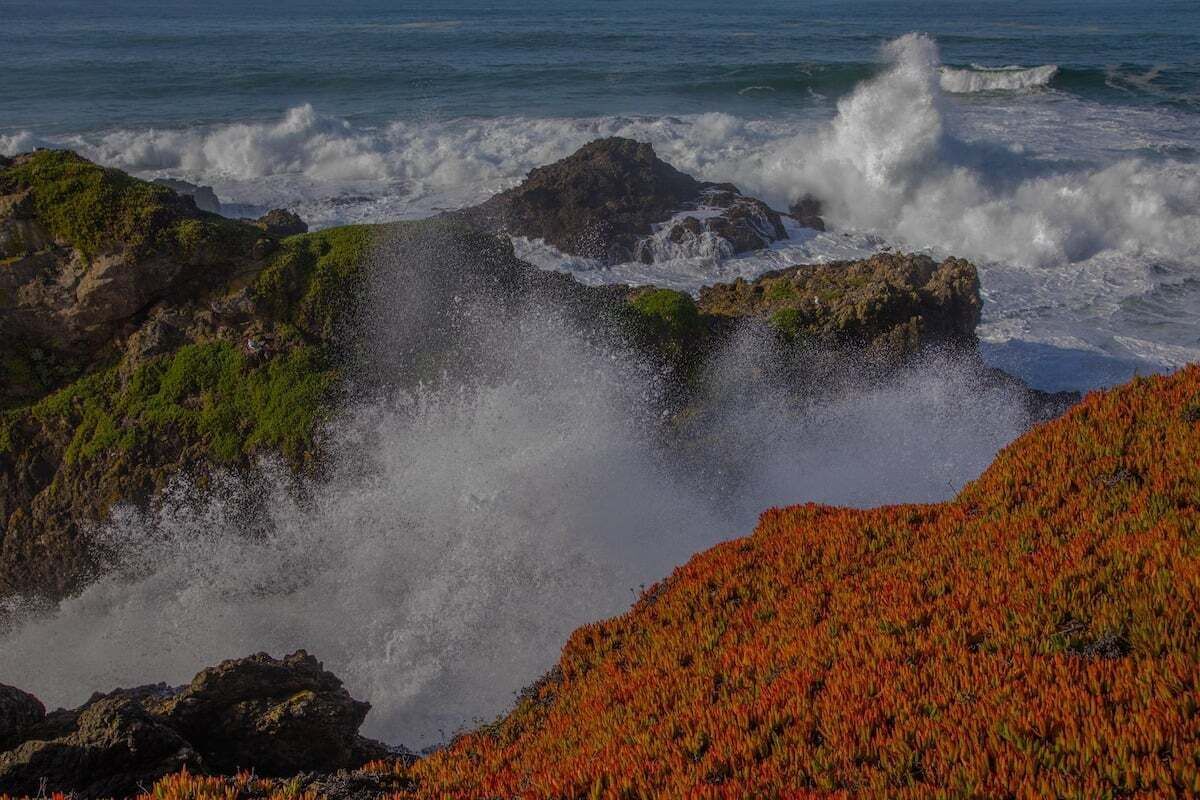 A coastal landscape with rocky terrain and waves crashing against the shore.