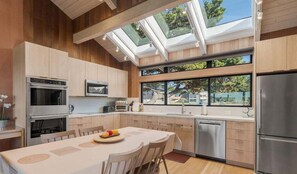 A modern kitchen with skylights, stainless steel appliances, and a dining area with a table and chairs.