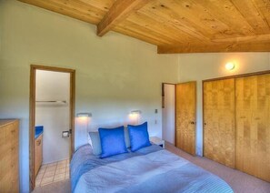 Ein Schlafzimmer mit Holzboden, einem Bett mit blauer Bettwäsche und einem Kleiderschrank.