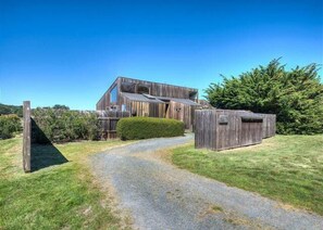 Ein modernes Holzhaus mit einem Schotterweg, der zu einem Holztor führt.