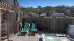 Une terrasse en bois avec des chaises longues et un jacuzzi.