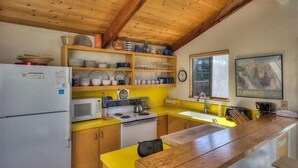 Une cuisine de taille réduite, dotée de meubles en bois, d’un four à micro-ondes, d’une cuisinière et d’un évier.