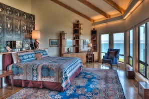 Ein Schlafzimmer mit einem großen Bett, Meerblick und einer Holzbalkendecke.