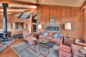 A cozy living room with a fireplace, wooden walls, and a sofa set.