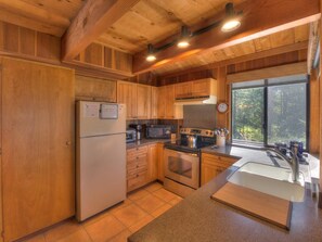 A kitchen with wooden cabinets, a refrigerator, a microwave, an oven, and a sink.