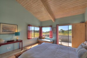 A bedroom with a large bed, a window seat, and a view of the outdoors. - Silver Mist | Pool with Stargazing Decks (The Sea Ranch)