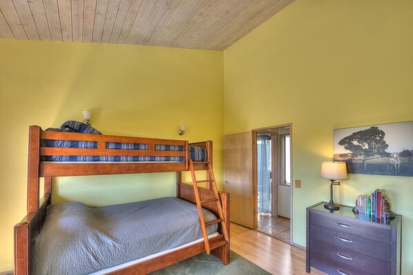 A room with a bunk bed, a desk with a lamp, and a painting on the wall.