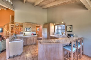 A spacious kitchen with wooden cabinets, a central island, and a bar area with stools.