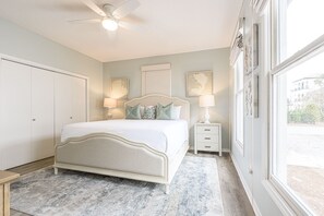 A bedroom with a bed, bedside tables, a ceiling fan, and artwork on the walls. - Golf Cart ~ Steps to the Beach ~ Community Pool (Santa Rosa Beach)