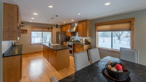 Una cocina moderna con armarios de madera, una isla central y un comedor con mesa y sillas.