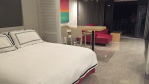 A hotel room with a large bed, a desk, and a red chair.