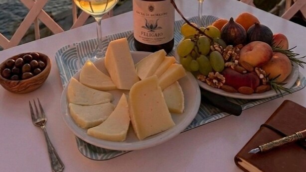 A table with a bottle of wine, glasses, cheese, fruits, and nuts, set against a sunset view. - "SEA HOUSE" DIRECTLY ON THE SEA (Pomonte)
