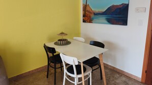 A dining area with a white table, black and white chairs, a patterned table runner, and a hanging lamp. - Attraktive Ferienwohnung am Luganer See (Porlezza)