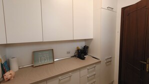 A kitchen with white cabinets, a wooden countertop, a coffee machine, and a door with a brass handle. - Attraktive Ferienwohnung am Luganer See (Porlezza)