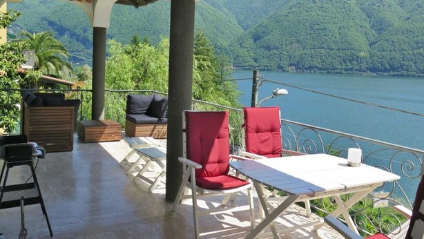 A balcony with outdoor seating, a table, and a view of a lake and mountains. - Attraktive Ferienwohnung am Luganer See (Porlezza)