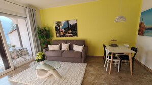 A living room with a sofa, coffee table, dining table, chairs, and a painting on the wall. - Attraktive Ferienwohnung am Luganer See (Porlezza)