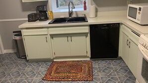 A compact kitchen with a sink, microwave, Bosch dishwasher, and a window with a view of trees. - Home Sweet Home, minutes to Great Lakes Naval Base (Lake Bluff)