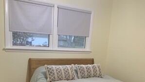 A bedroom with a bed, wooden headboard, two windows with blinds, a ceiling fan, and a view of a house outside. - Home Sweet Home, minutes to Great Lakes Naval Base (Lake Bluff)