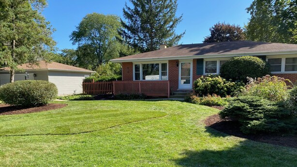 A residential house with a well-maintained lawn, a wooden fence, and various shrubs. - Home Sweet Home, minutes to Great Lakes Naval Base (Lake Bluff)
