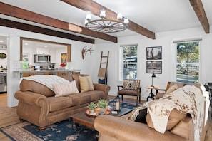 A cozy living room with a brown leather sofa, a coffee table, and a rustic ceiling light.