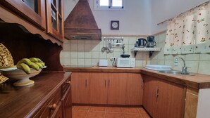 Eine kleine Küche mit Holzschränken, einer Mikrowelle, einem Spülbecken und einem Fenster darüber.