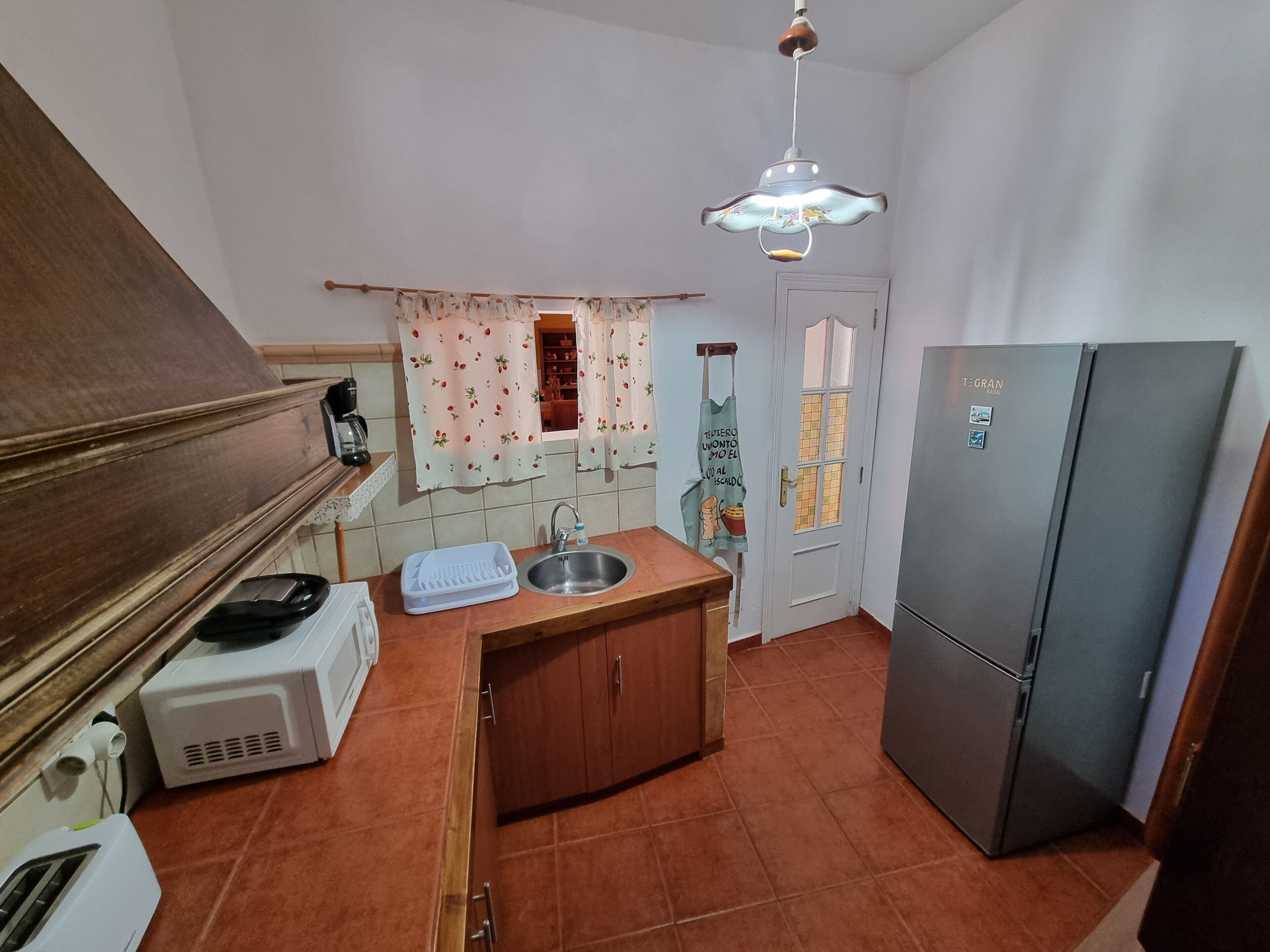 Una cocina compacta con un lavabo, un refrigerador y un microondas.