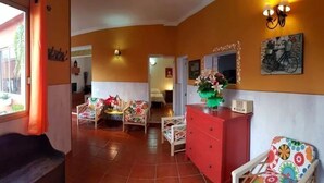 Ein Zimmer mit einer Couch, einem roten Schminktisch und zwei Stühlen mit Blumenmuster.