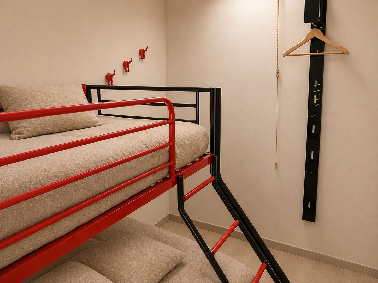 Een stapelbed met een rood frame, een enkel bed met een beige matras en een zwart wandplankje met een kapstok.