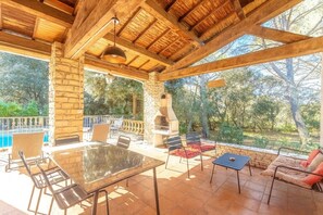 An outdoor patio with a stone wall, a grill, and a pool. - Le Domaine d'Alèzen (Grans)