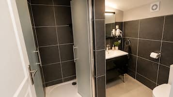 Uma casa de banho moderna com chuveiro, sanita e lavatório.